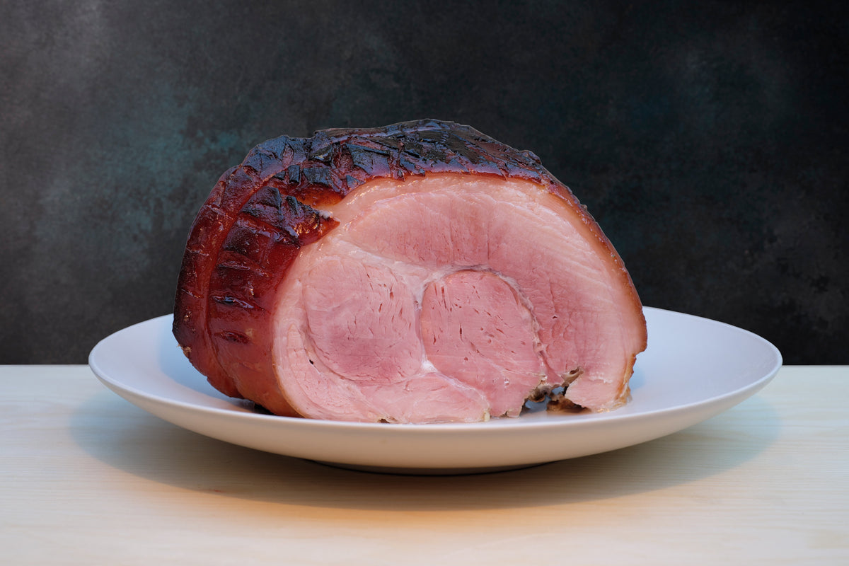 One of our delicious whole celebration hams that has been poached, glazed and roasted, sitting on a plate and ready to eat.