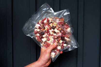 A hand holding a vacuum pouch of chunky London Smoke & Cure dry-aged grade A lardons.